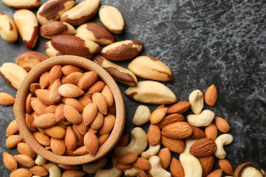 Siyah dumanlı arka planda badem ve farklı fındıklı ahşap kase, metin için yer