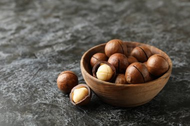 Siyah dumanlı arka planda lezzetli macadamia fındıkları olan kase.