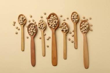 Bej arkaplanda nohut bulunan tahta kaşıklar.