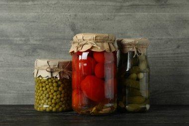 Gri arka planda tahta masada turşulu kavanozlar.