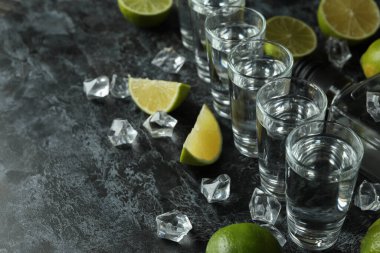 Bir şişe votka, shot, buz küpleri ve siyah dumanlı masada limon dilimleri.