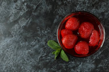 Siyah dumanlı masada bir bardak çilek reçeli