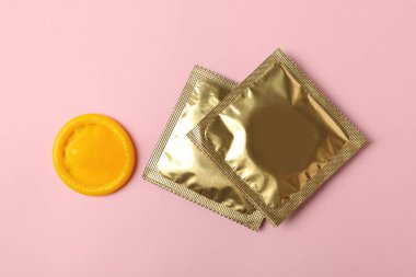 Sarı prezervatif ve pembe arka planda boş prezervatif.