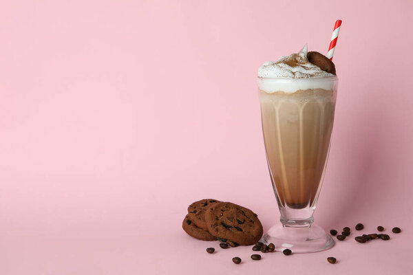 Glass of milkshake, coffee seeds and cookies on pink background