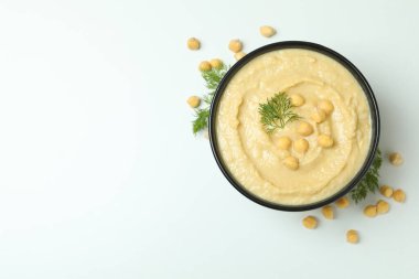 Bir kase humus ve beyaz desenli arkaplanda dereotu.