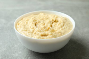 Gri arka planda bir kase taze humus.
