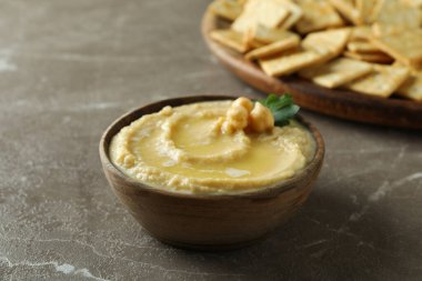 Kraker tepsisi ve gri arka planda bir kase humus.
