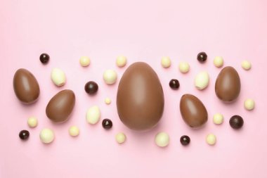 Paskalya çikolatası ve pembe arka planda şekerler.
