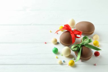 Beyaz ahşap masa üzerinde paskalya çikolatası ve şeker.