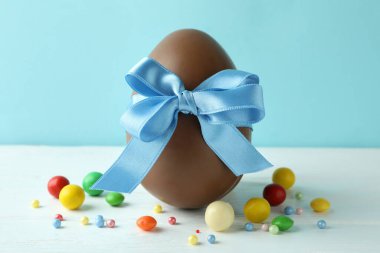 Paskalya çikolatası yumurtası ve beyaz ahşap masada şekerler.