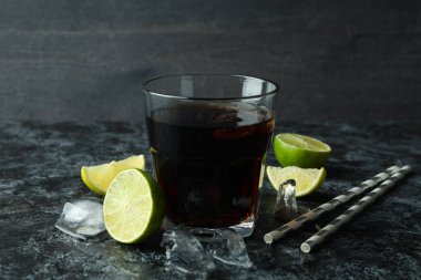 Bir bardak Küba Libre ve siyah dumanlı masa malzemeleri.