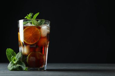 Bir bardak Küba Libre 'si ve karanlık arka planda naneli şeker.