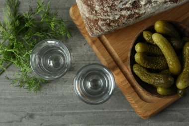 Gri masada votka, turşu, ekmek ve dereotu.