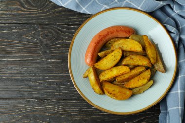 Patates kızartması, sosis ve ahşap arka planda mutfak havlusu.