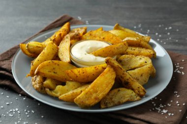 Patates dilimli tabak ve koyu dokulu soslu arka plan.