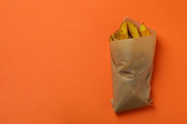 Turuncu arka planda patates dilimleri olan fırın kağıdı.