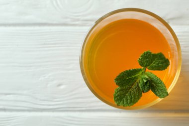 Beyaz ahşap masada nane şekerli bir bardak turuncu jöle.