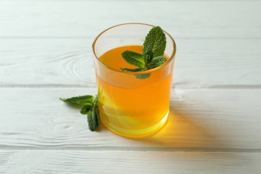 Beyaz ahşap masada nane şekerli bir bardak turuncu jöle.