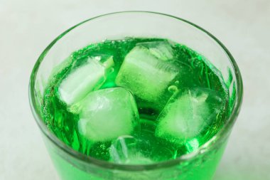 Beyaz desenli arka planda bir bardak yeşil soda.