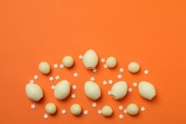 Paskalya çikolatası yumurtaları ve turuncu arka planda serpiştirmeler