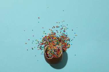 Kırık paskalya çikolatası yumurtası mavi arka planda serpiştirilmiş.