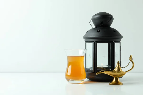 Glass of tea, Ramadan lamp and lantern on white background