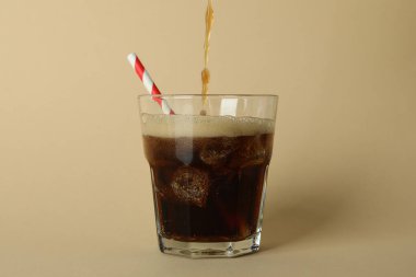 Kola, bej arka planda bir bardağa dökülür.