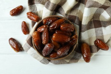 Mutfak peçetesinde beyaz ahşap arka planda kurutulmuş hurma kasesi.