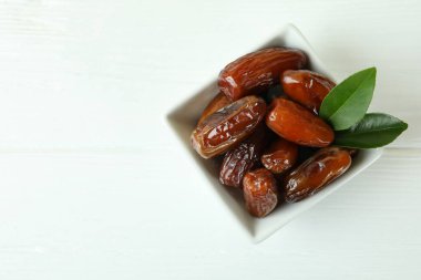 Beyaz ahşap masada kurutulmuş hurma kasesi.