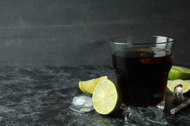 Bir bardak Küba Libre ve siyah dumanlı masa malzemeleri.