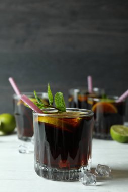 Küba Libre kokteylleri ahşap masada, karanlık arka planda.