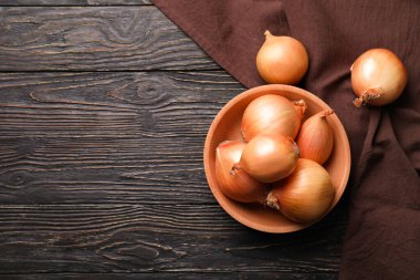 Tahta zemin üzerinde taze soğan ve mutfak havlusu olan bir kase.
