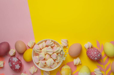 Paskalya yumurtası, marşmelov ve kağıt yaprakları renk arka planında