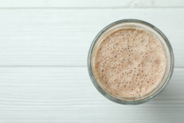 Beyaz ahşap masada bir bardak çikolatalı milkshake.