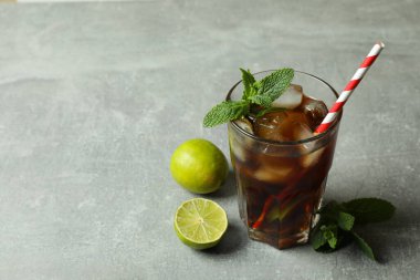 Bir bardak Küba Libre 'si ve gri arka plandaki malzemeler.