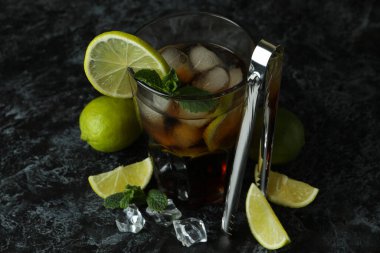 Bir bardak Küba Libre ve siyah dumanlı arka plandaki malzemeler