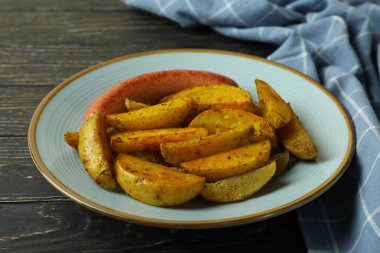 Patates kızartması, sosis ve ahşap arka planda mutfak havlusu.