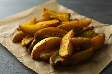 Koyu desenli arka planda patates dilimleri olan kağıt fırını.