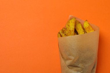 Turuncu arka planda patates dilimleri olan fırın kağıdı.