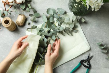 Kadın okaliptüs kağıdını gri desenli masaya sarar.