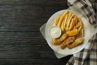 Mutfak havlusuyla ahşap zemin üzerinde kızarmış balık ve patates kızartması tabağı