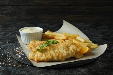 Siyah dumanlı masada kızarmış balık ve patates kızartması.