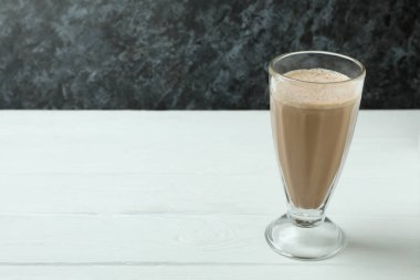Beyaz ahşap masada bir bardak çikolatalı milkshake.