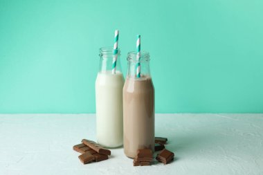 Süt ve milkshake şişeleri ve naneli arka planda çikolata parçaları.