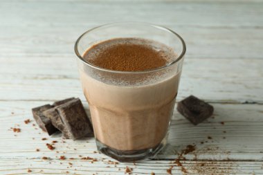 Bir bardak çikolatalı milkshake ve ahşap masada çikolata parçaları.