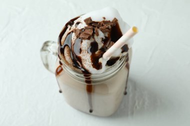 Beyaz dokulu masada bir bardak çikolatalı milkshake.