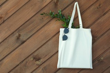 Tahta arka planda dallı ve güneş gözlüklü bir çanta.