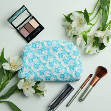 Beyaz arka planda kozmetik çanta, kozmetik ve alstromerya.