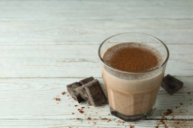 Bir bardak çikolatalı milkshake ve ahşap masada çikolata parçaları.