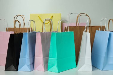 Beyaz arkaplanda farklı renkli kağıt torbaları var.